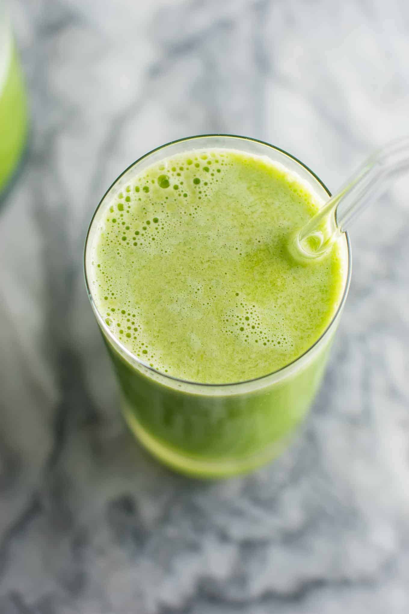 green juice in a glass with a glass straw