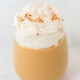 pumpkin smoothie in a glass with whipped cream on top