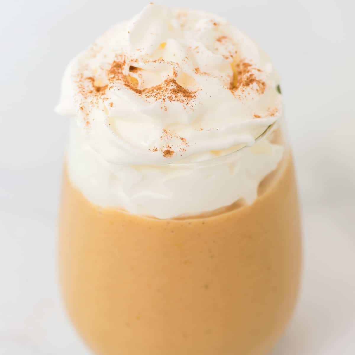 pumpkin smoothie in a glass with whipped cream on top