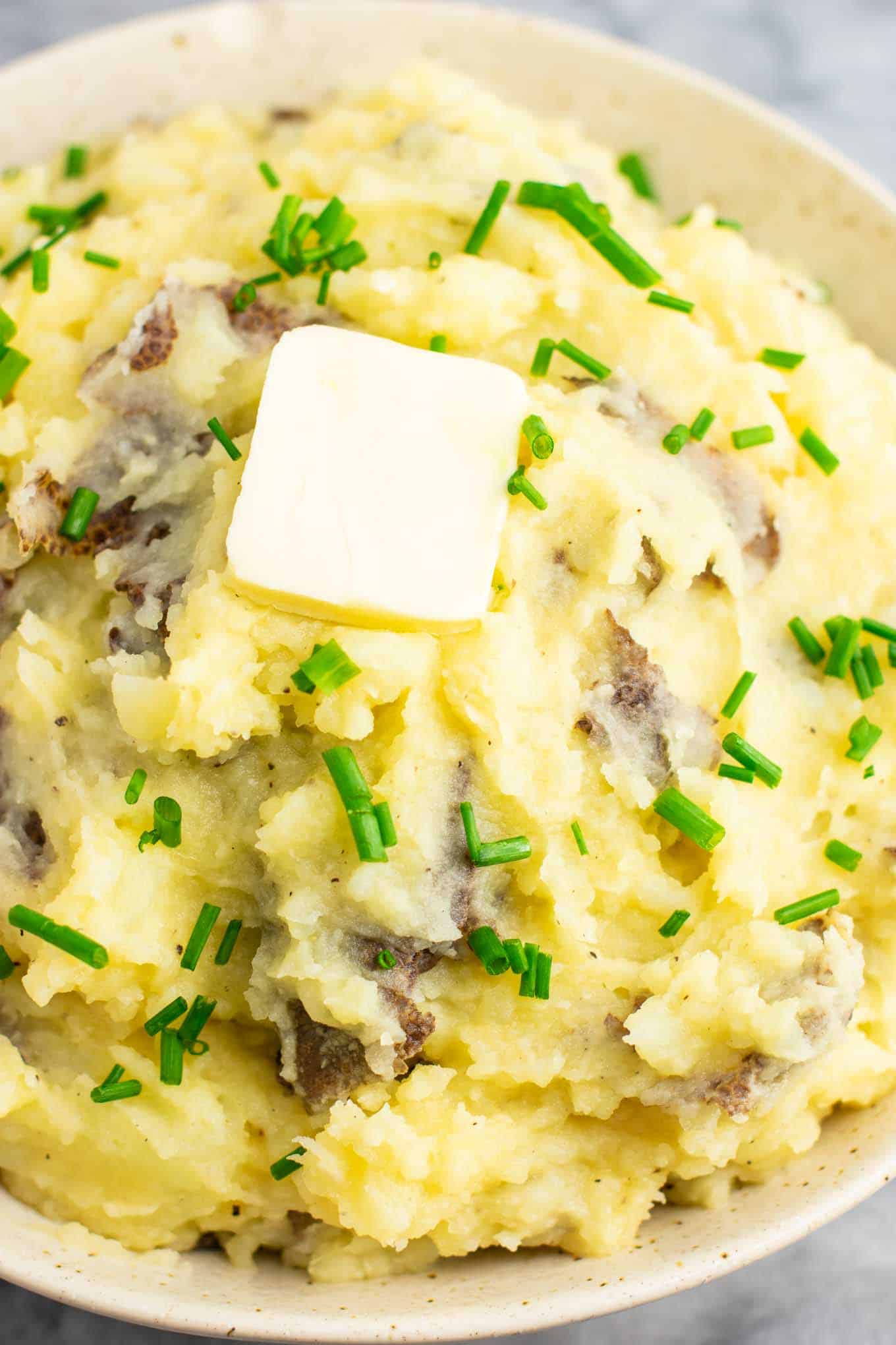 vegan mashed potatoes in a bowl topped with butter and chives