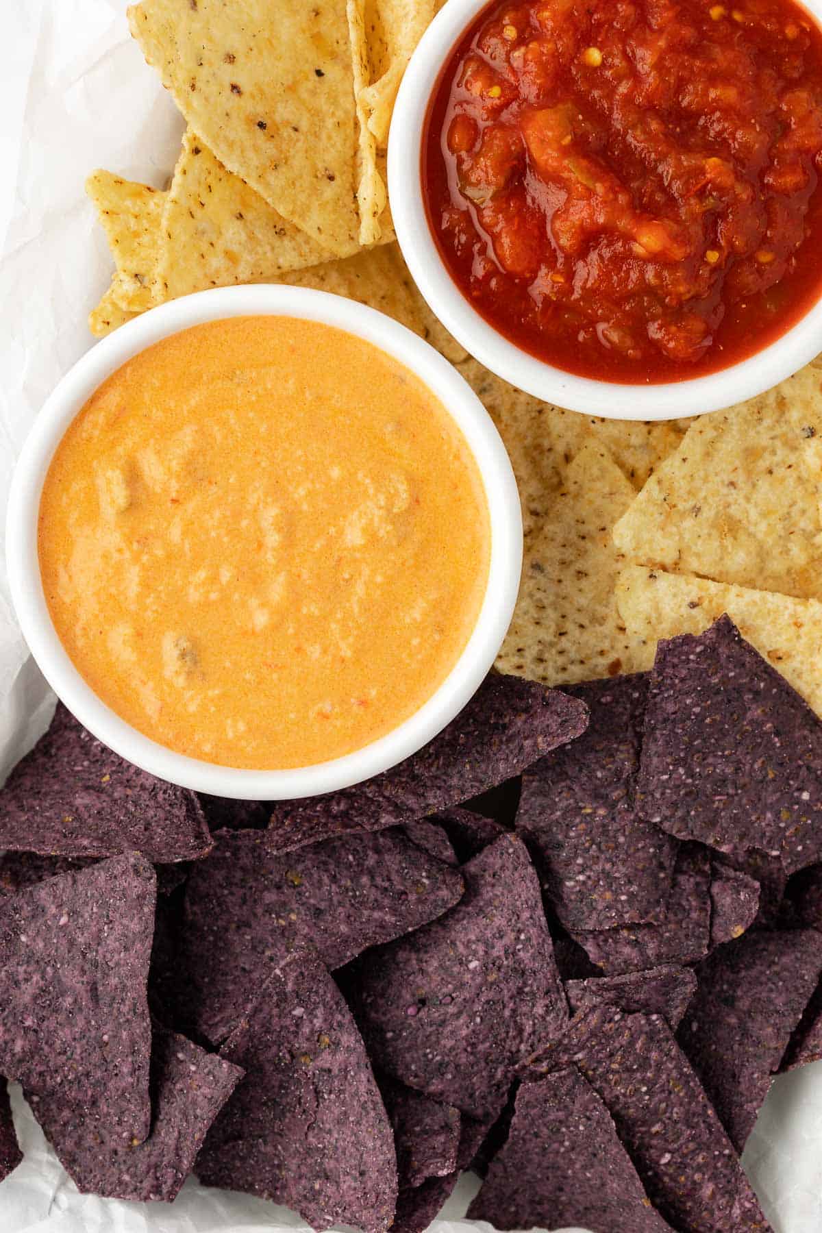 ramekins of queso dip and salsa surrounded by tortilla chips