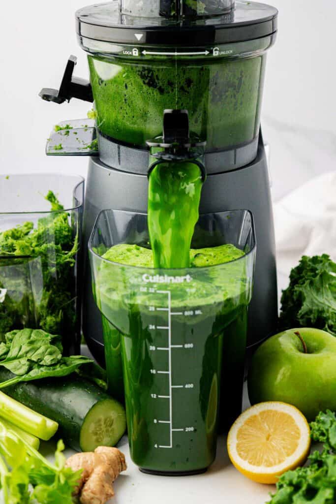 green juice pouring out of a juicer
