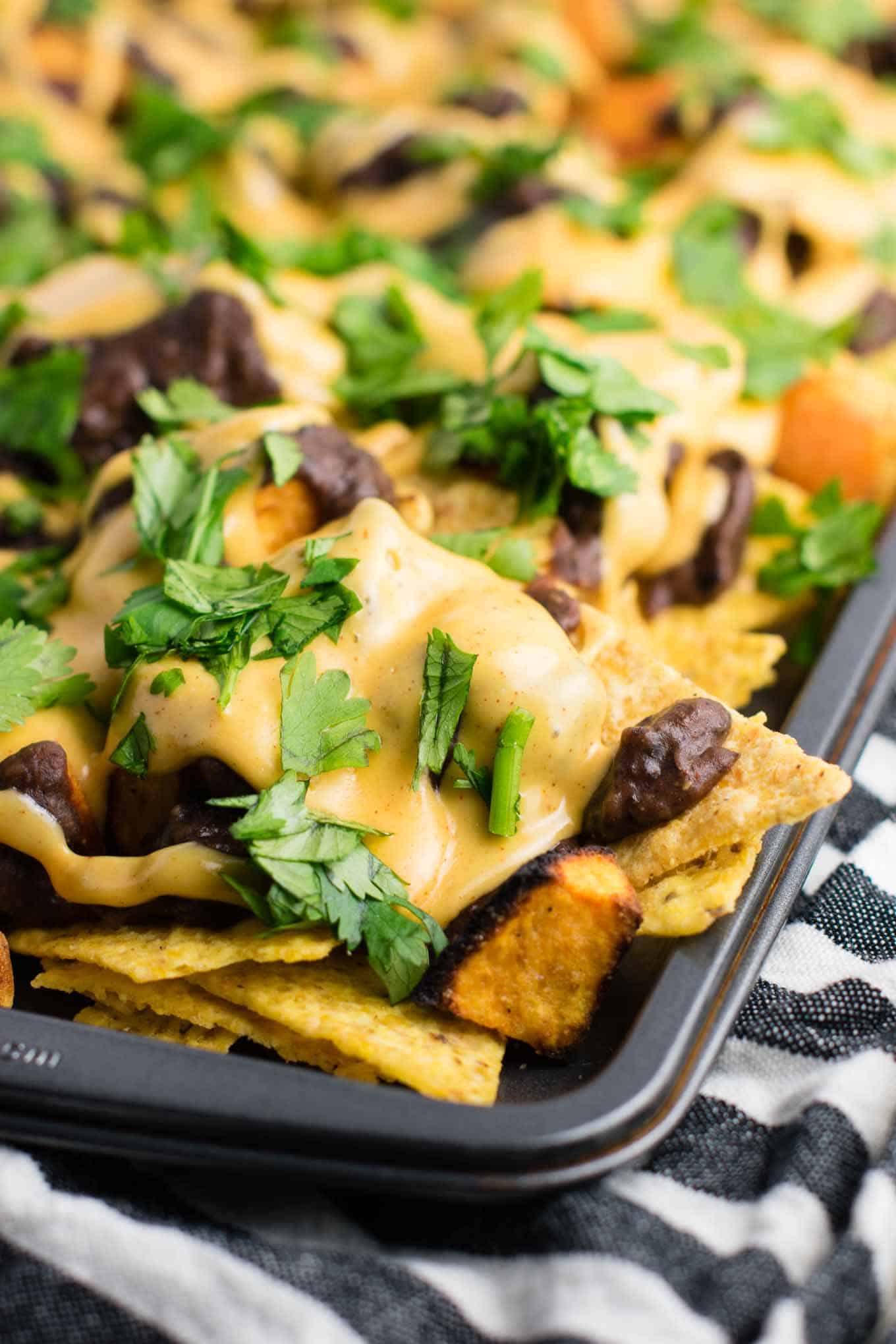 30 minute sweet potato refried bean nachos with homemade refried beans and cheese sauce. An impressive vegetarian dinner made in less than half an hour! #vegetarian #sweetpotatonachos #30minutemeal