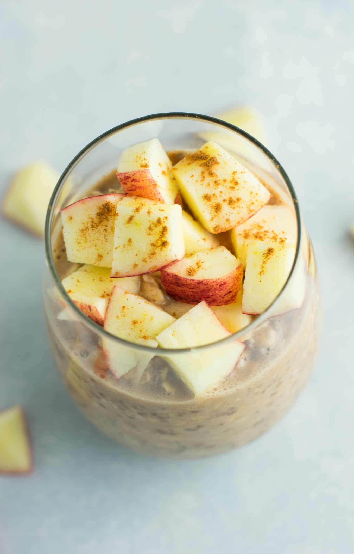 overnight oats in a glass topped with chopped apples and cinnamon