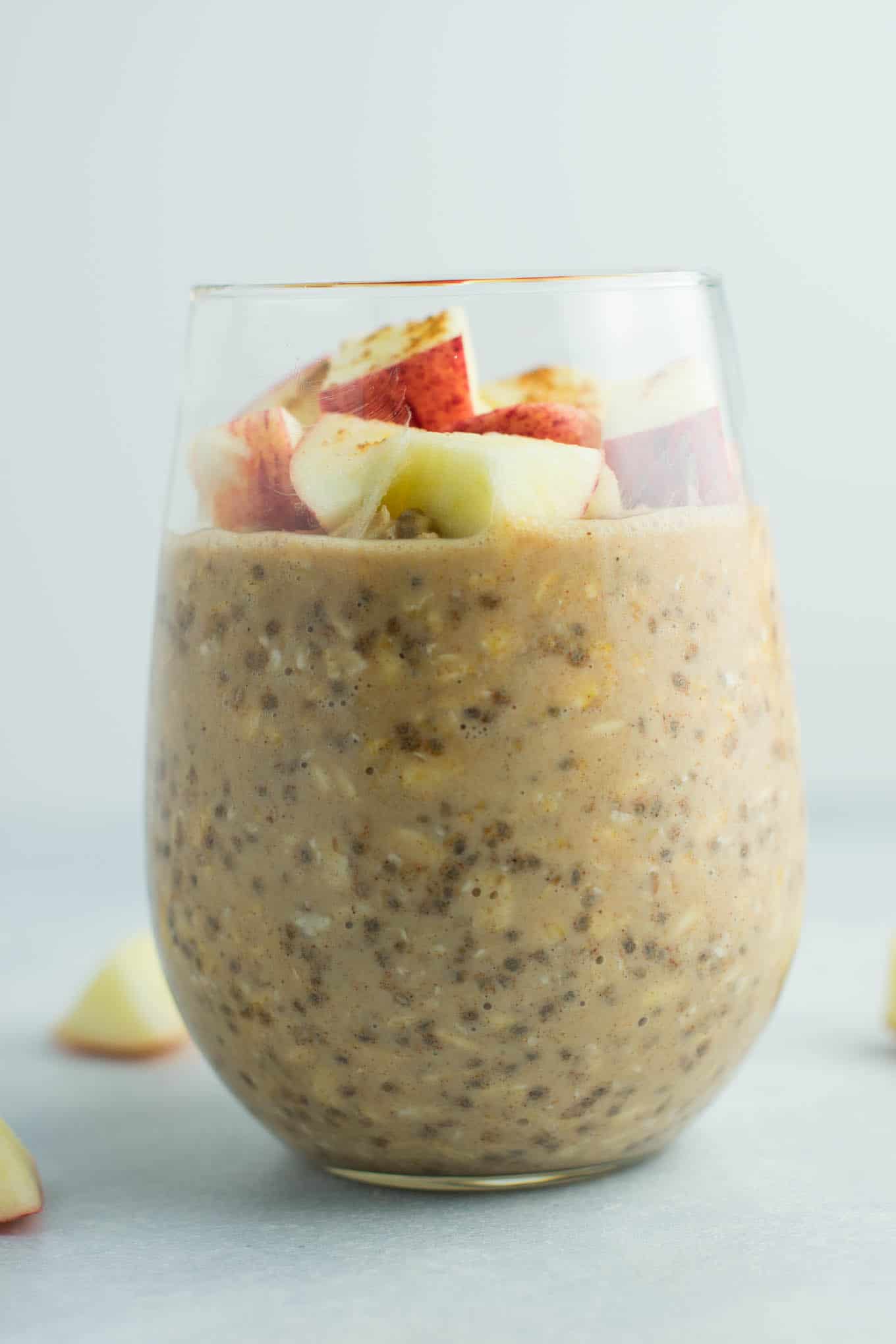 overnight oats in a glass topped with chopped apples and cinnamon