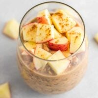 overnight oats in a glass topped with diced apples and cinnamon