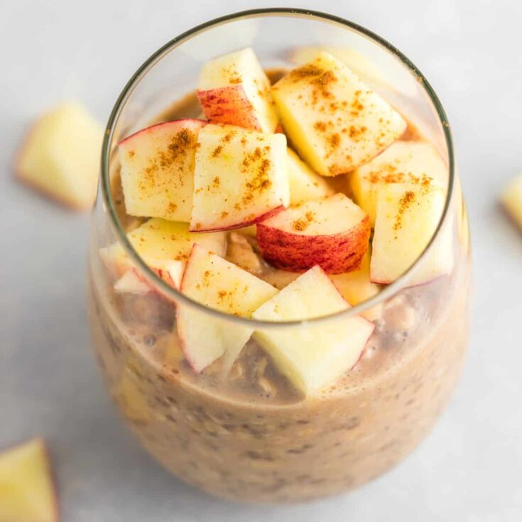 overnight oats in a glass topped with diced apples and cinnamon