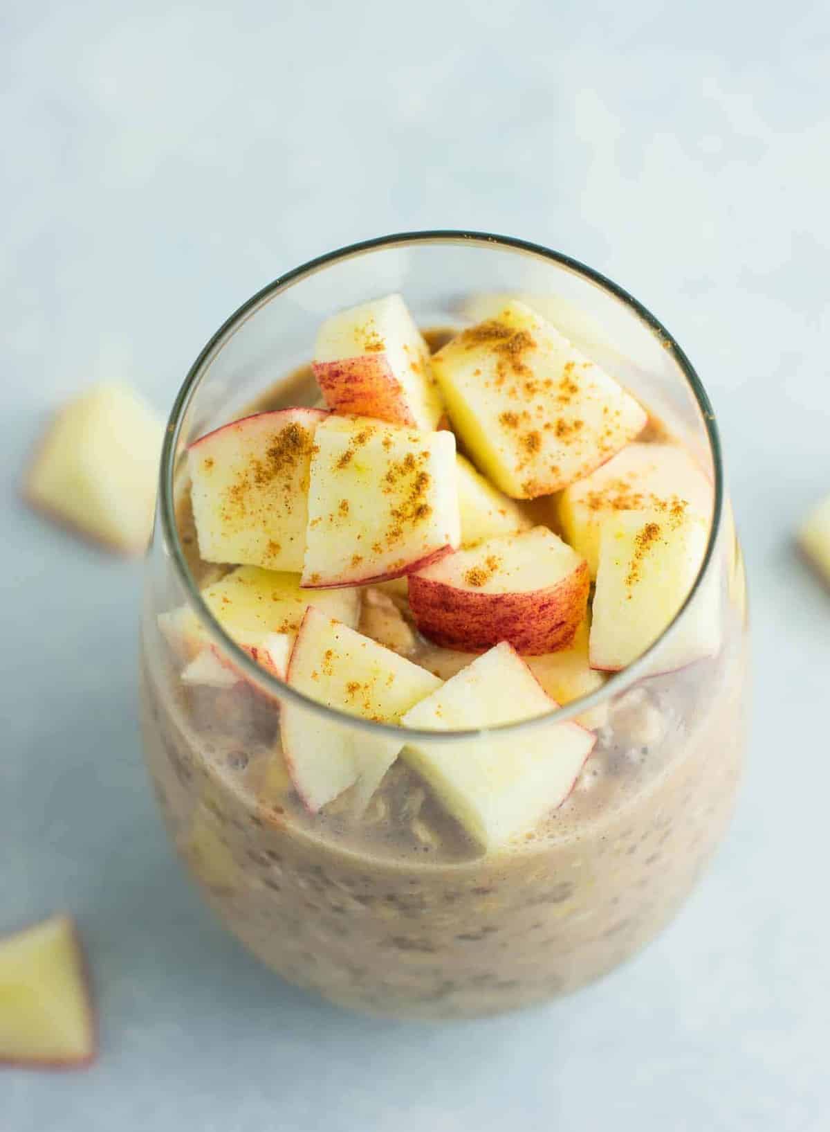 overnight oats in a glass topped with chopped apples and cinnamon