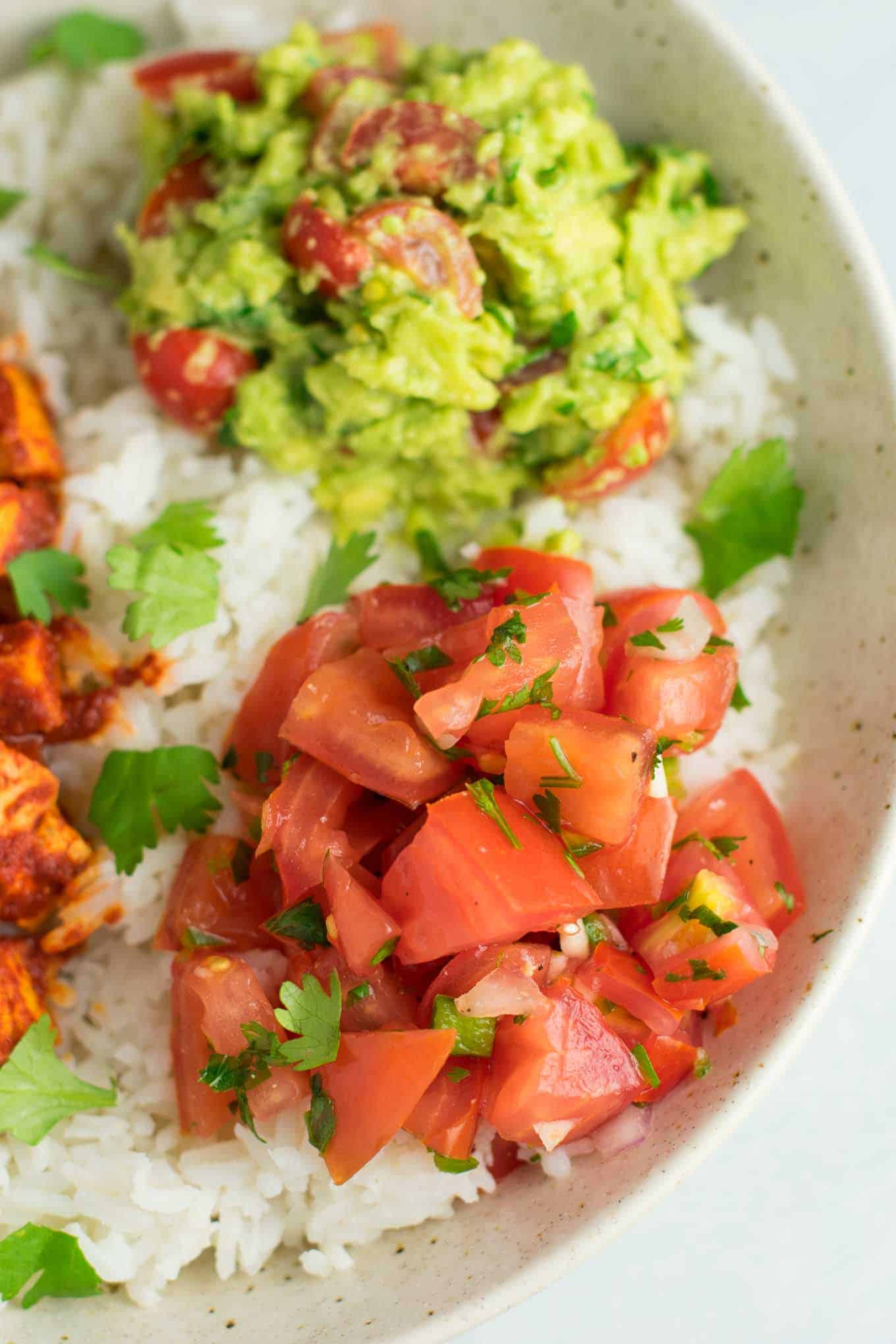 Easy enchilada tofu burrito bowls with homemade guacamole and salsa. Bring chipotle to your kitchen with this delicious recipe! #vegan #burritobowls #tofuburritobowls