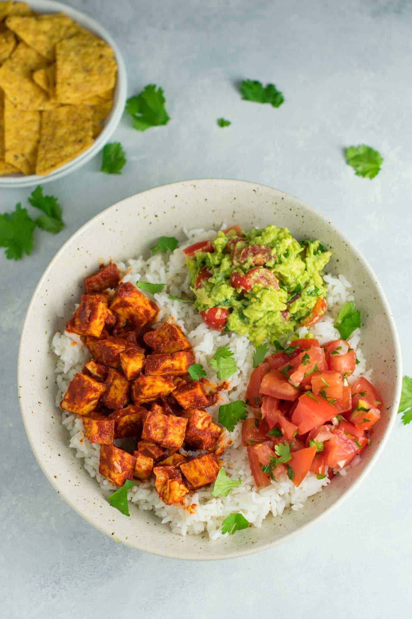 Easy enchilada tofu burrito bowls with homemade guacamole and salsa. Bring chipotle to your kitchen with this delicious recipe! #vegan #burritobowls #tofuburritobowls