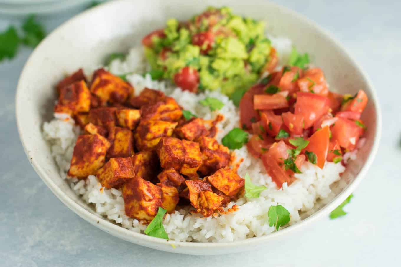 Easy enchilada tofu burrito bowls with homemade guacamole and salsa. Bring chipotle to your kitchen with this delicious recipe! #vegan #burritobowls #tofuburritobowls