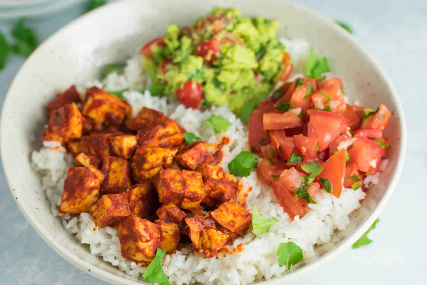 Easy enchilada tofu burrito bowls with homemade guacamole and salsa. Bring chipotle to your kitchen with this delicious recipe! #vegan #burritobowls #tofuburritobowls