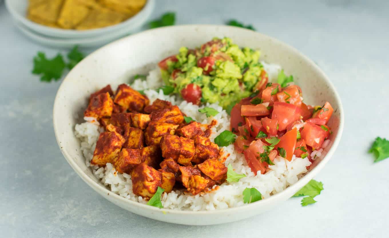 Easy enchilada tofu burrito bowls with homemade guacamole and salsa. Bring chipotle to your kitchen with this delicious recipe! #vegan #burritobowls #tofuburritobowls