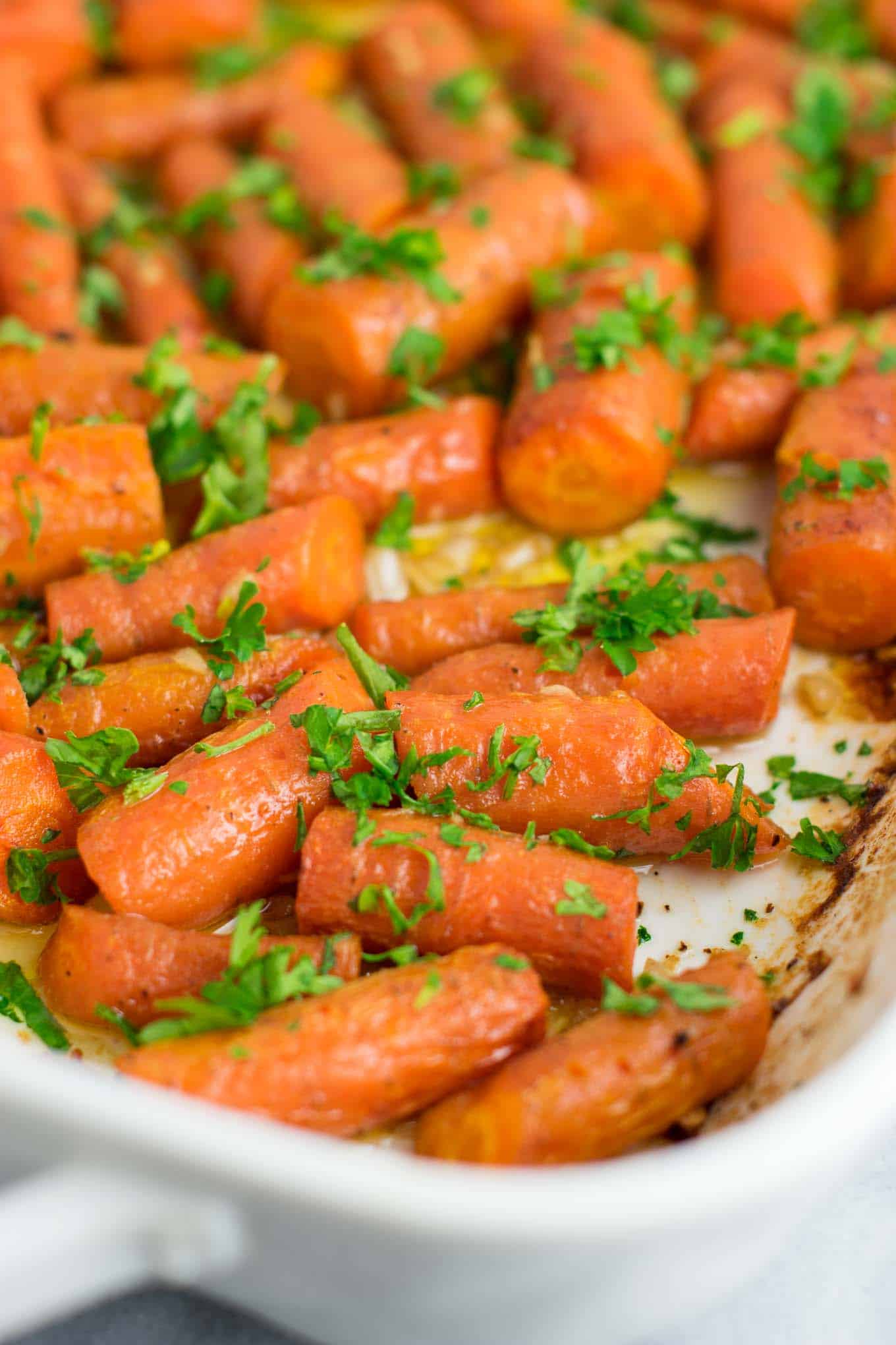 Garlic butter roasted carrots recipe with fresh parsley. A delicious vegan friendly side dish recipe that will disappear in minutes! #vegan #roastedcarrots #garlicbutter #garlicbuttercarrots #sidedishes #vegetables