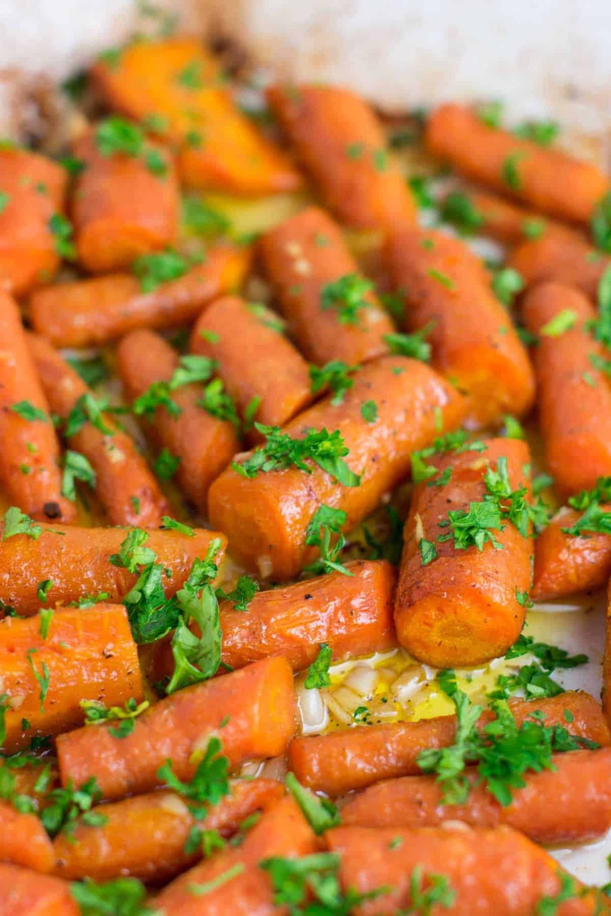 Garlic butter roasted carrots recipe with fresh parsley. A delicious vegan friendly side dish recipe that will disappear in minutes! #vegan #roastedcarrots #garlicbutter #garlicbuttercarrots #sidedishes #vegetables