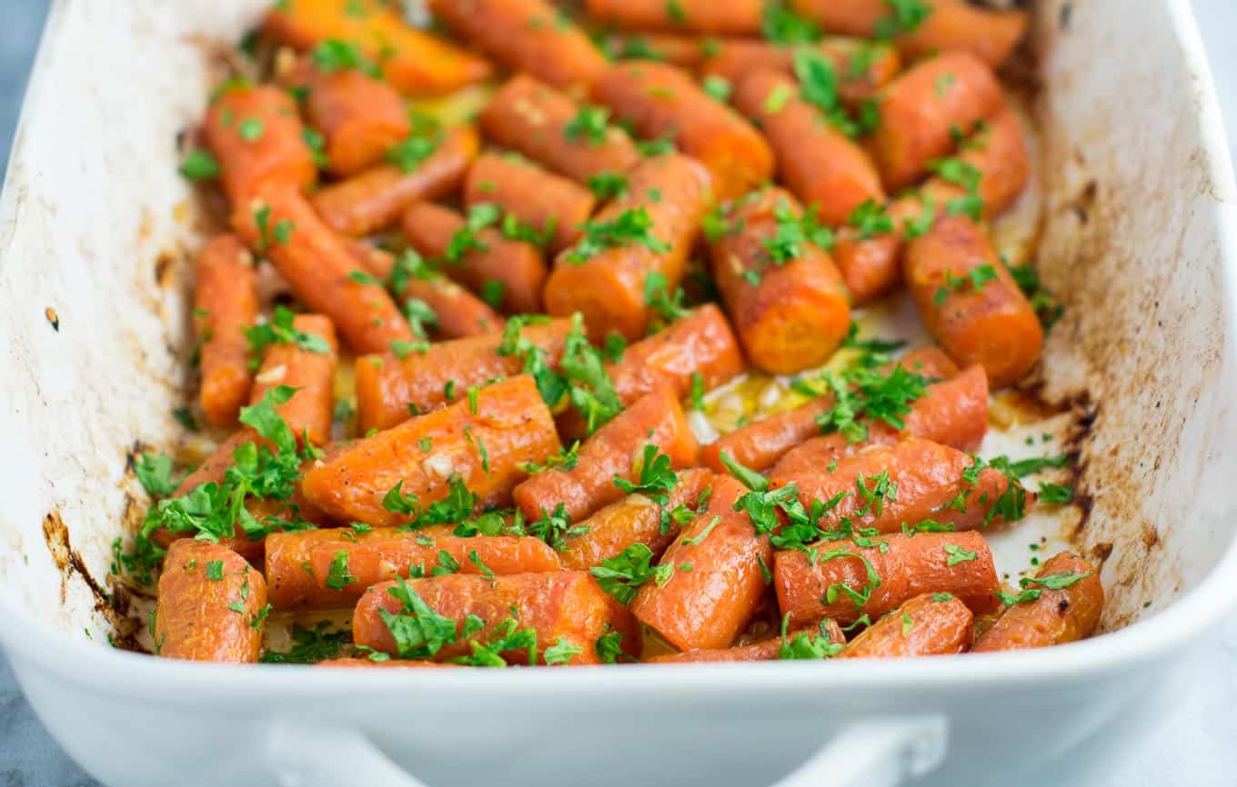 Garlic butter roasted carrots recipe with fresh parsley. A delicious vegan friendly side dish recipe that will disappear in minutes! #vegan #roastedcarrots #garlicbutter #garlicbuttercarrots #sidedishes #vegetables