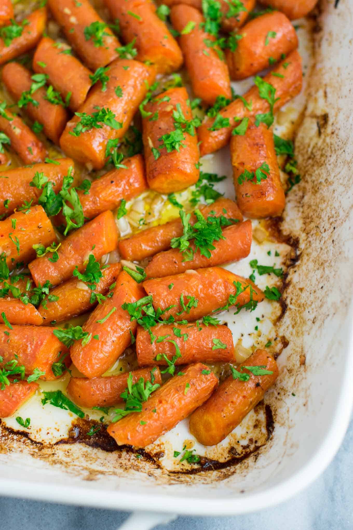 Garlic butter roasted carrots recipe with fresh parsley. A delicious vegan friendly side dish recipe that will disappear in minutes! #vegan #roastedcarrots #garlicbutter #garlicbuttercarrots #sidedishes #vegetables