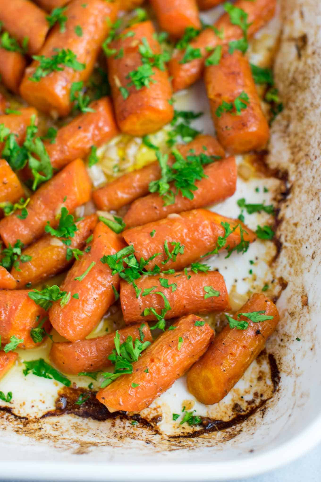 Garlic butter roasted carrots recipe with fresh parsley. A delicious vegan friendly side dish recipe that will disappear in minutes! #vegan #roastedcarrots #garlicbutter #garlicbuttercarrots #sidedishes #vegetables