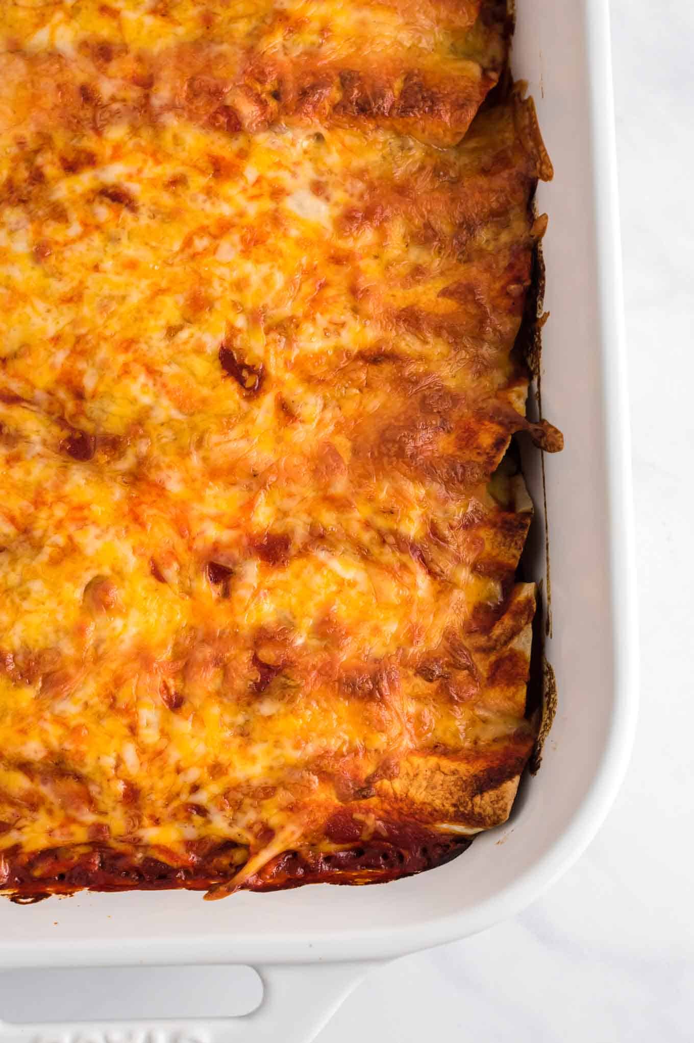 enchiladas in a white baking dish covered with cheese