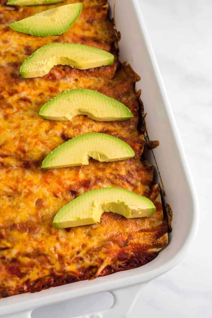 enchiladas with sliced avocado from a side angle