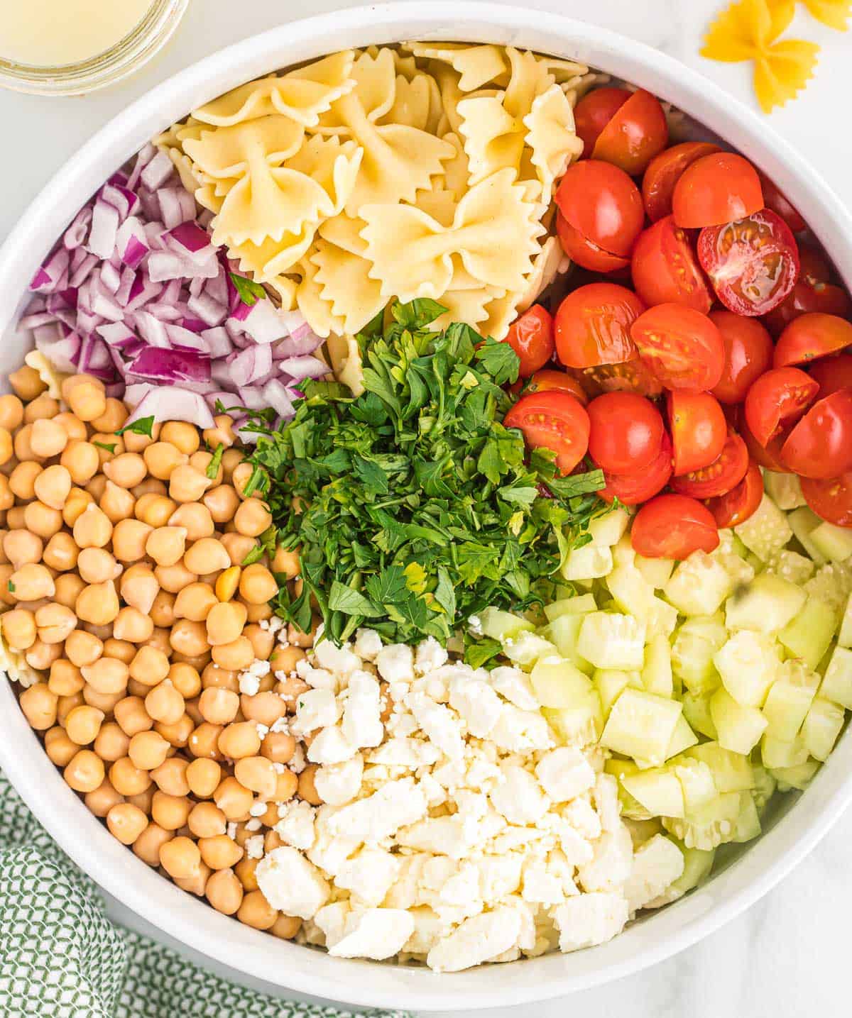 ingredients for pasta salad placed in groups in a mixing bowl