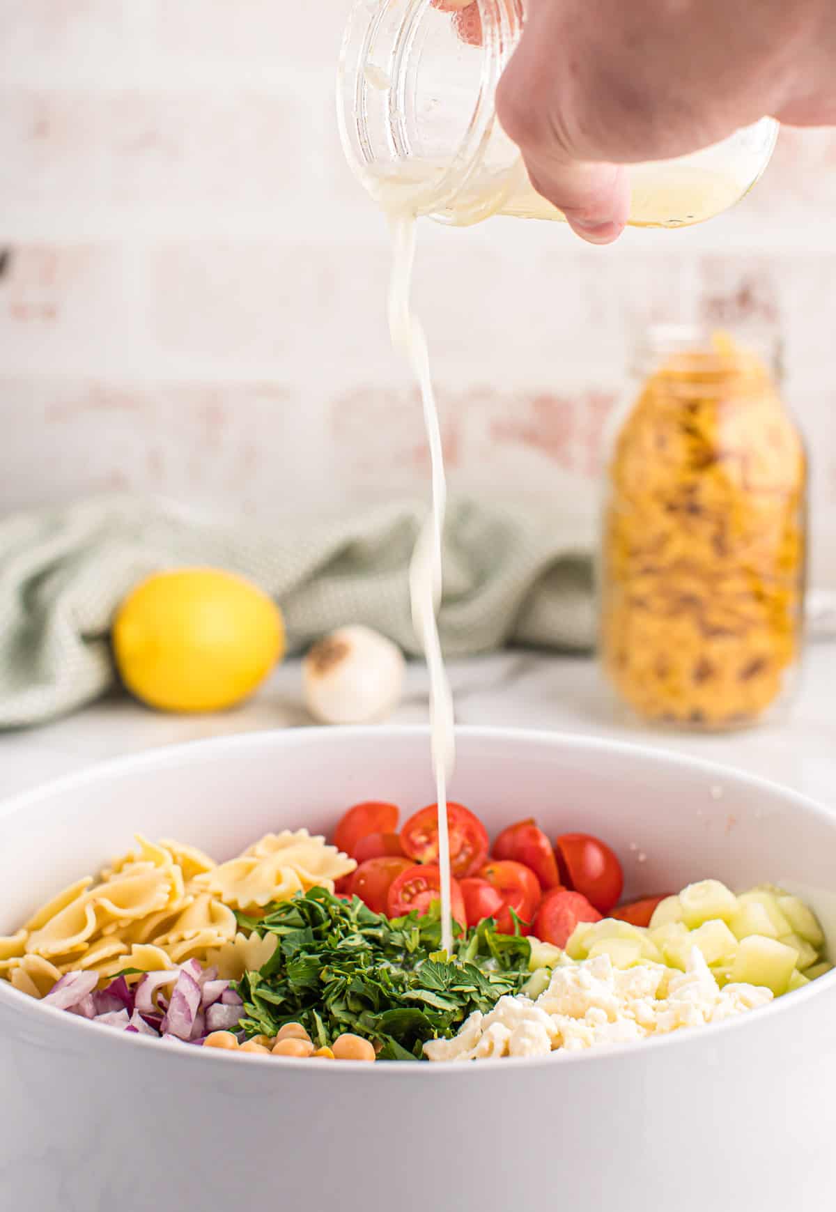 pouring the dressing over the pasta salad