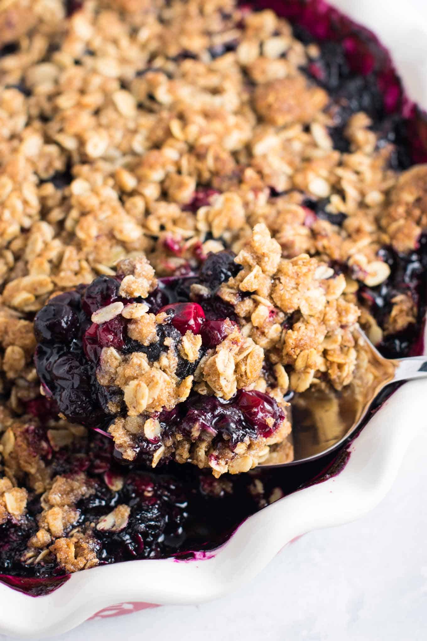 spoon taking a scoop of cranberry blueberry crisp