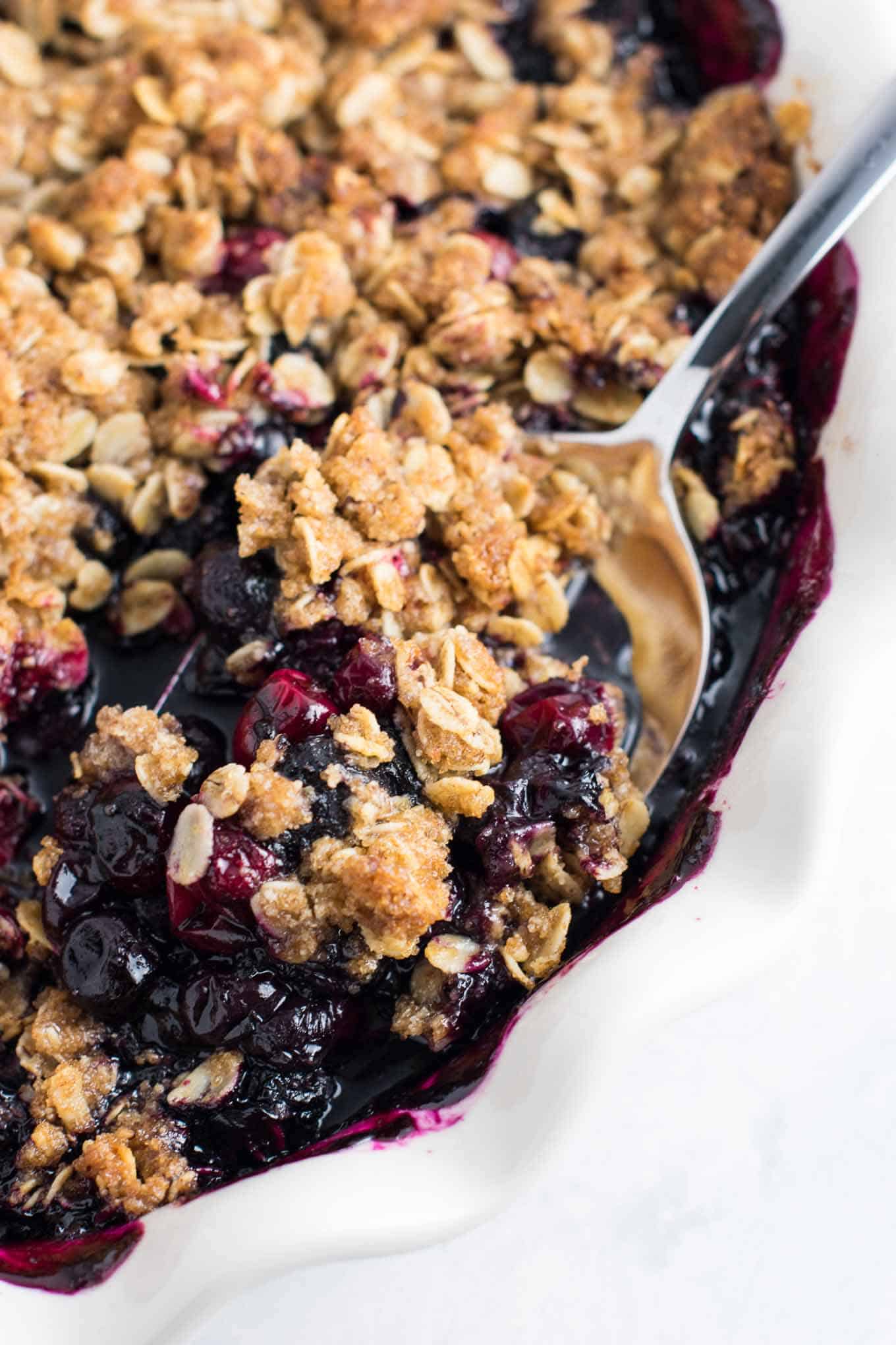 spoon taking a scoop of cranberry blueberry crisp