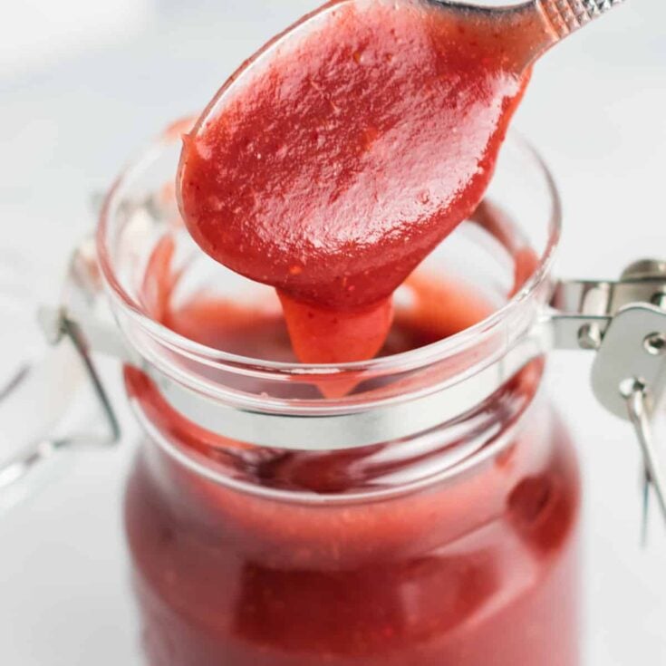 taking a spoonful of cranberry apple butter from a jar