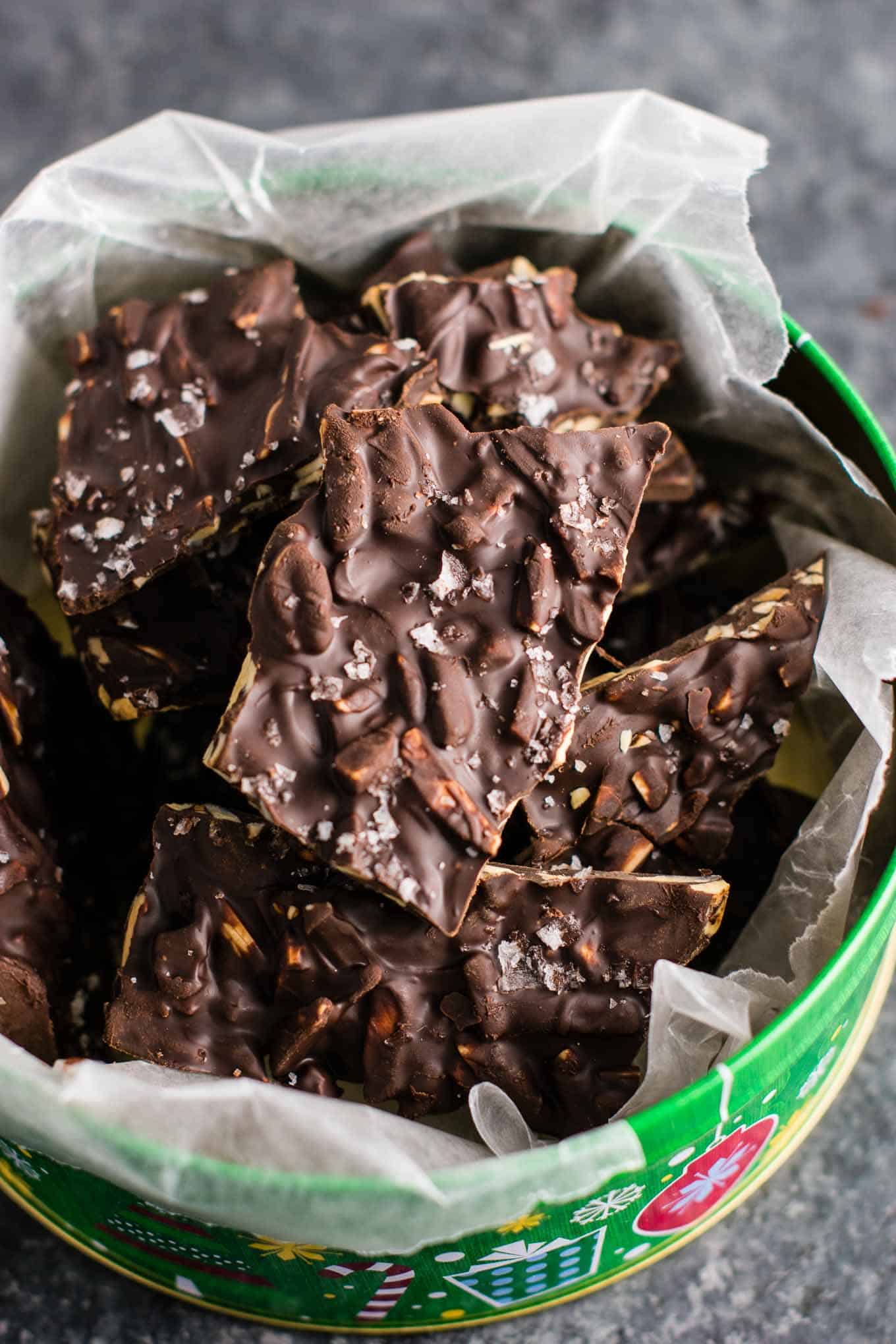 chocolate almond bark in a christmas tin lined with wax paper