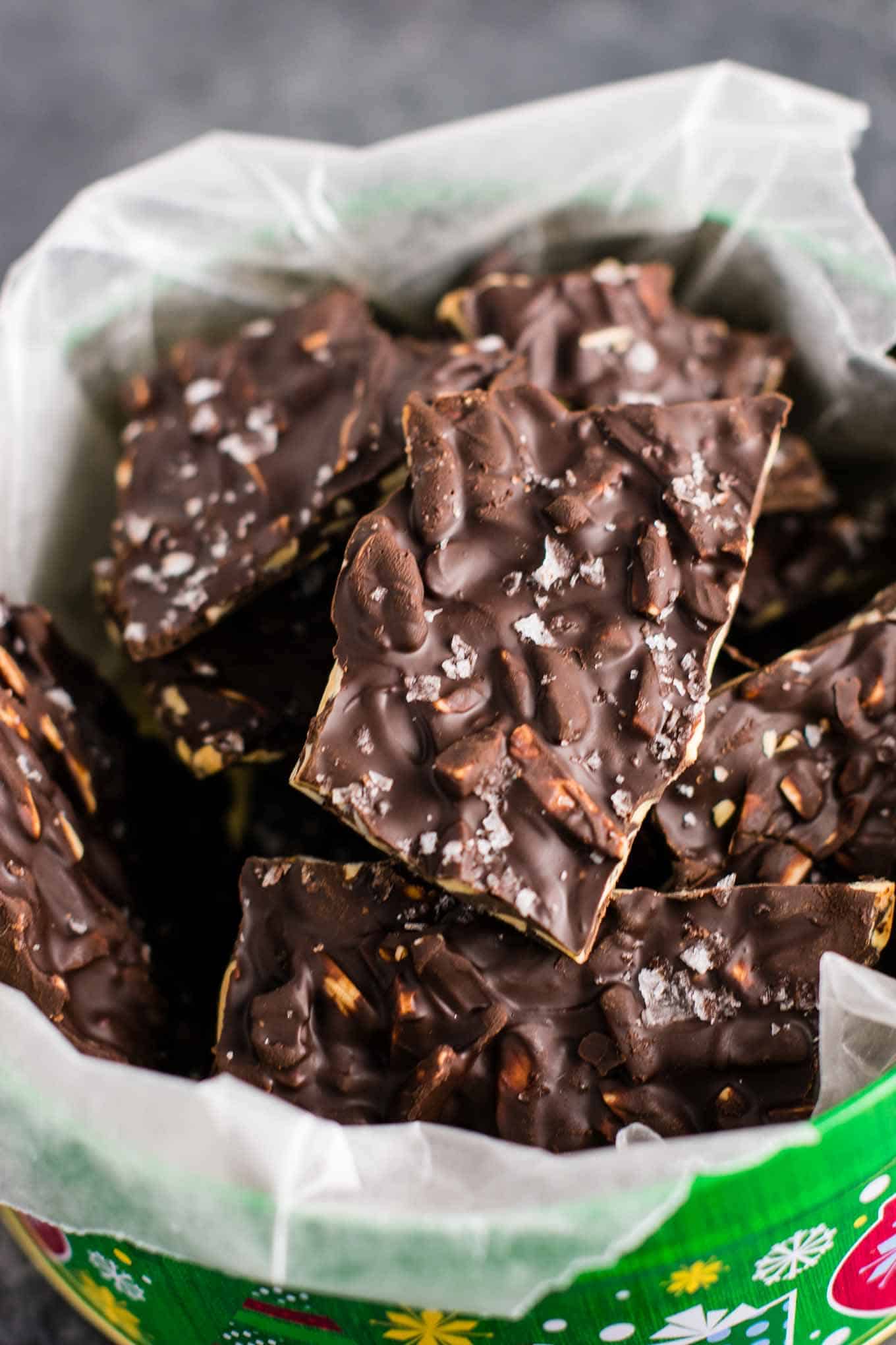 chocolate almond bark in a christmas tin lined with wax paper