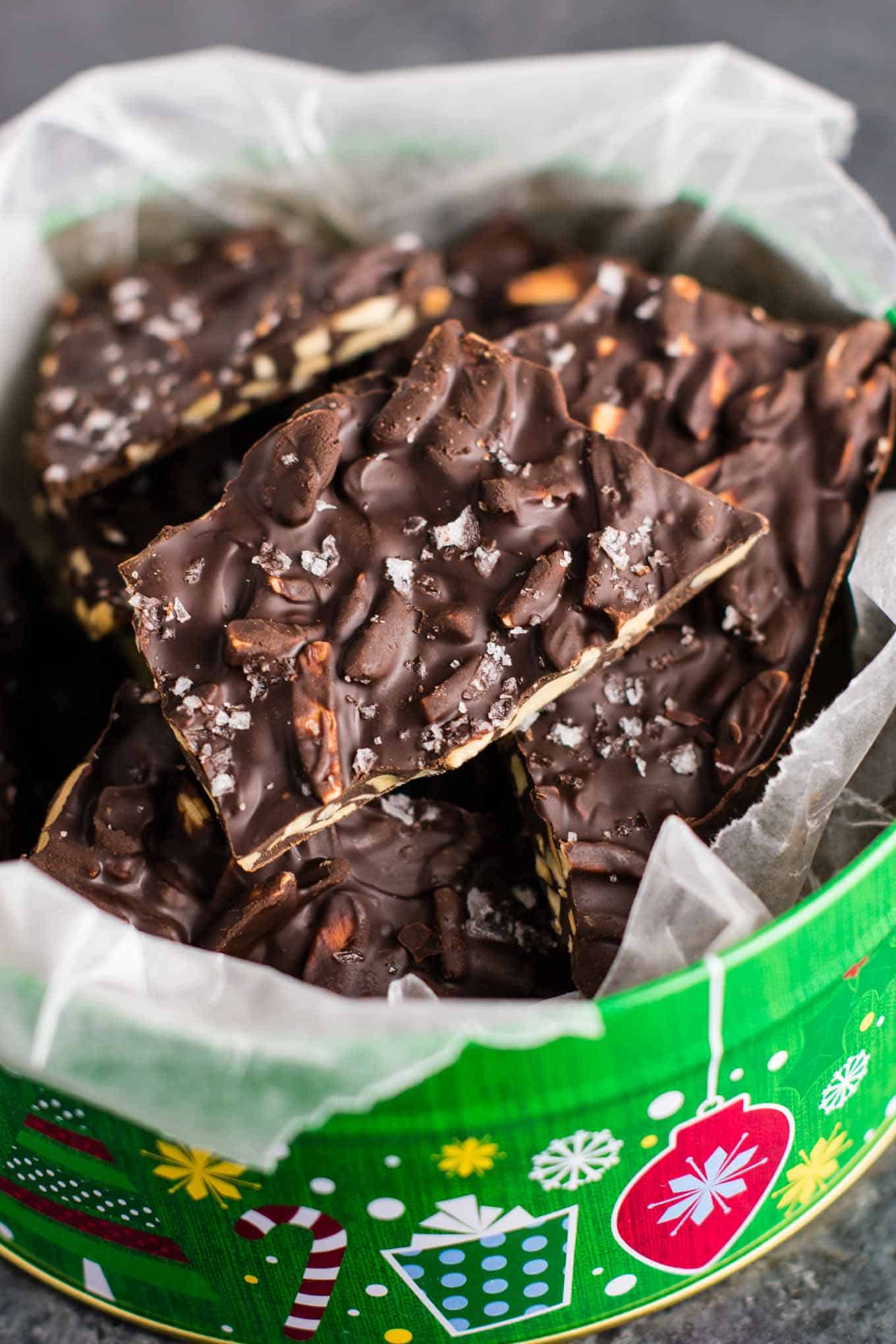 chocolate almond bark in a christmas tin lined with wax paper