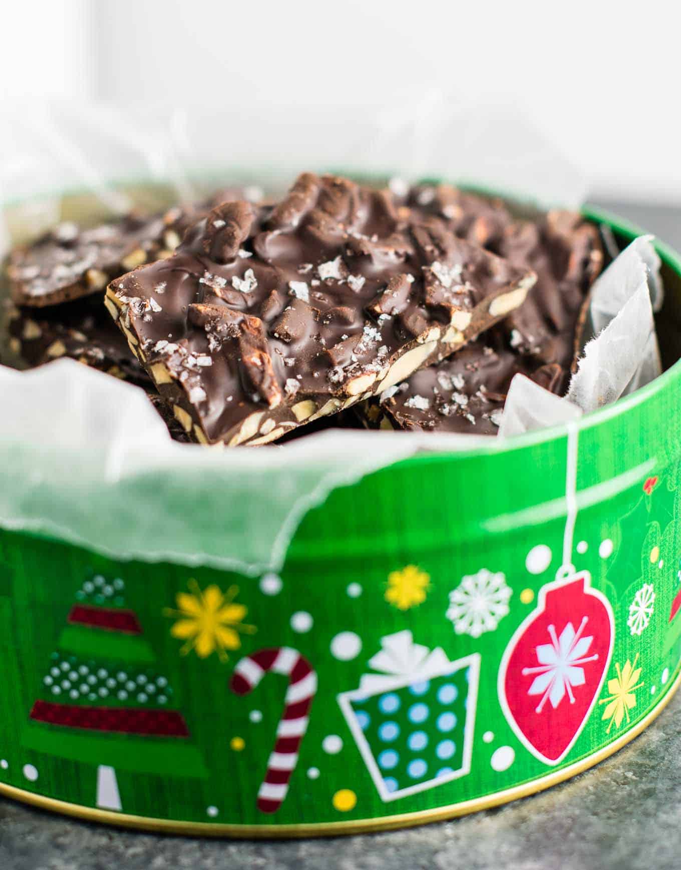 chocolate almond bark in a christmas tin lined with wax paper