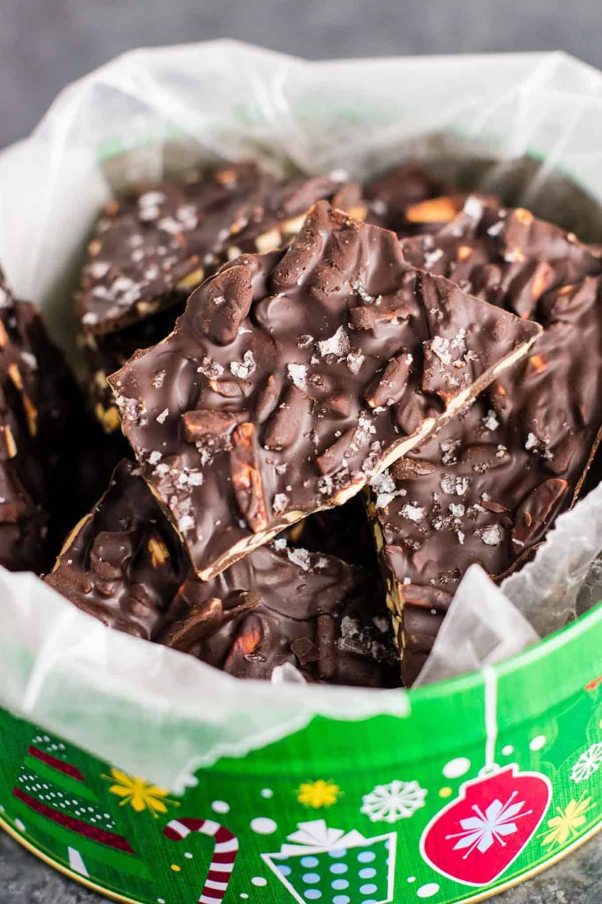 chocolate almond bark in a christmas tin lined with wax paper