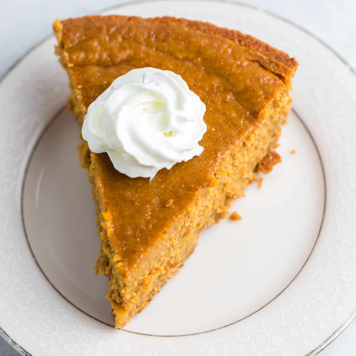 a slice of pumpkin pie on a plate topped with whipped cream