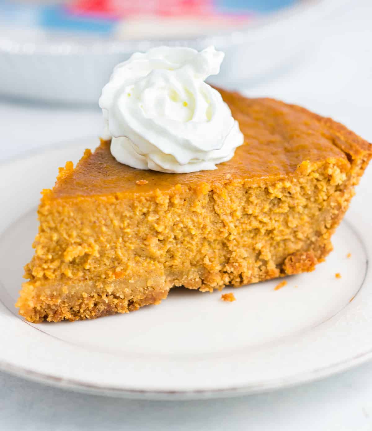 a slice of pumpkin pie on a plate topped with whipped cream