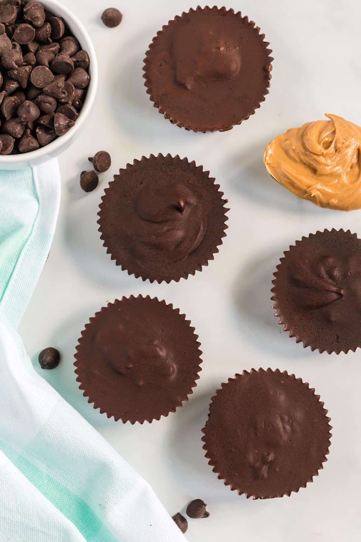 peanut butter cups lined up next to a spoon of peanut butter