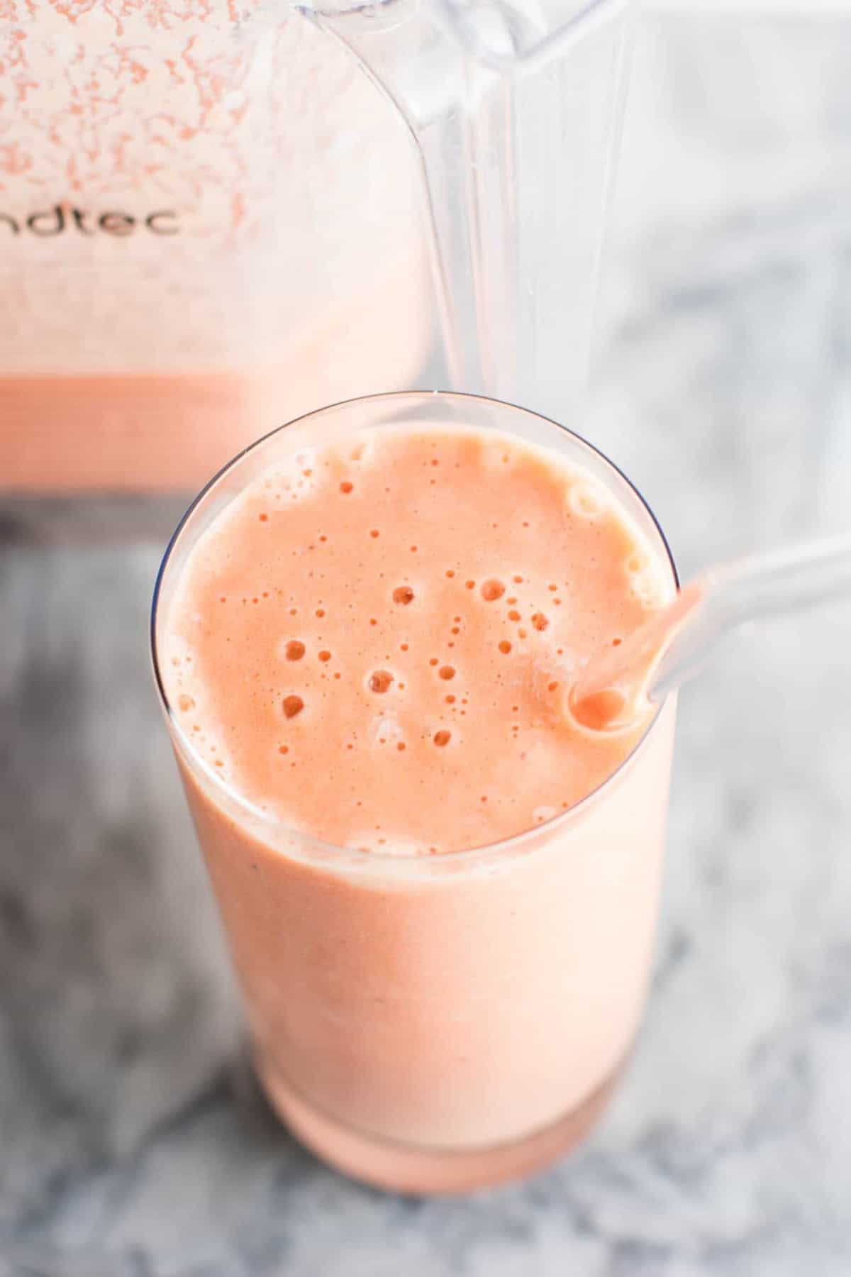 carrot cake smoothie in a glass with a glass straw