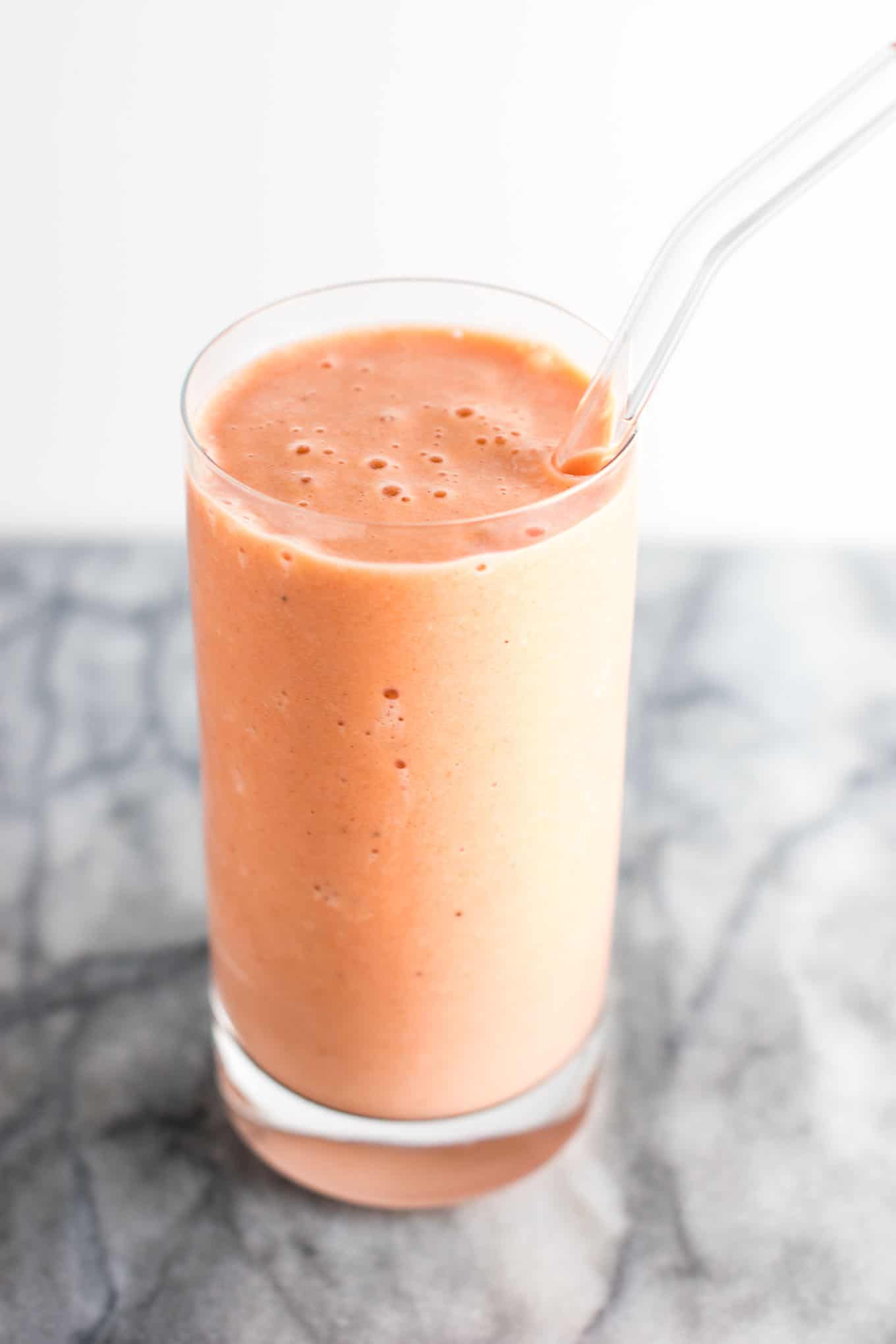 carrot cake smoothie in a glass with a glass straw