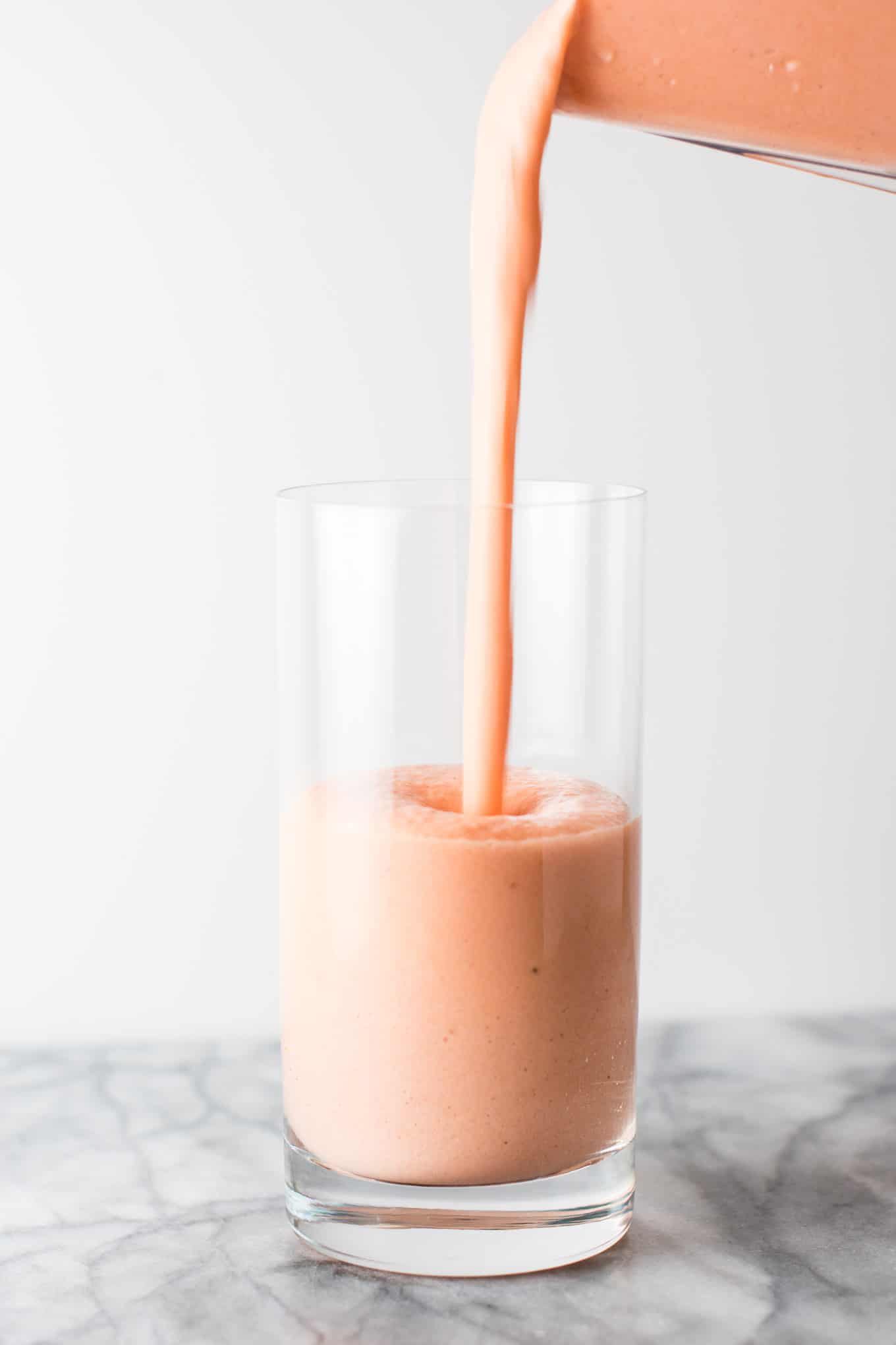 smoothie being poured into a glass from a blender