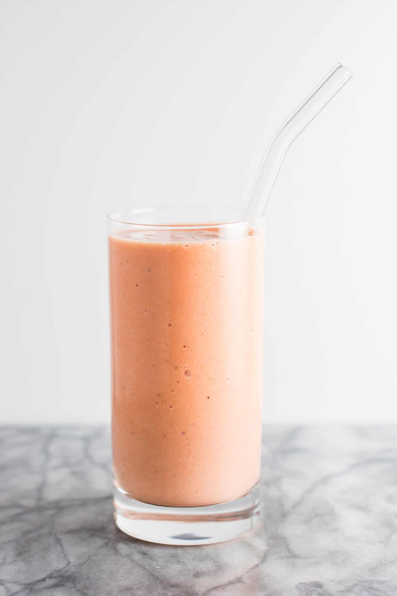 carrot cake smoothie in a glass with a glass straw