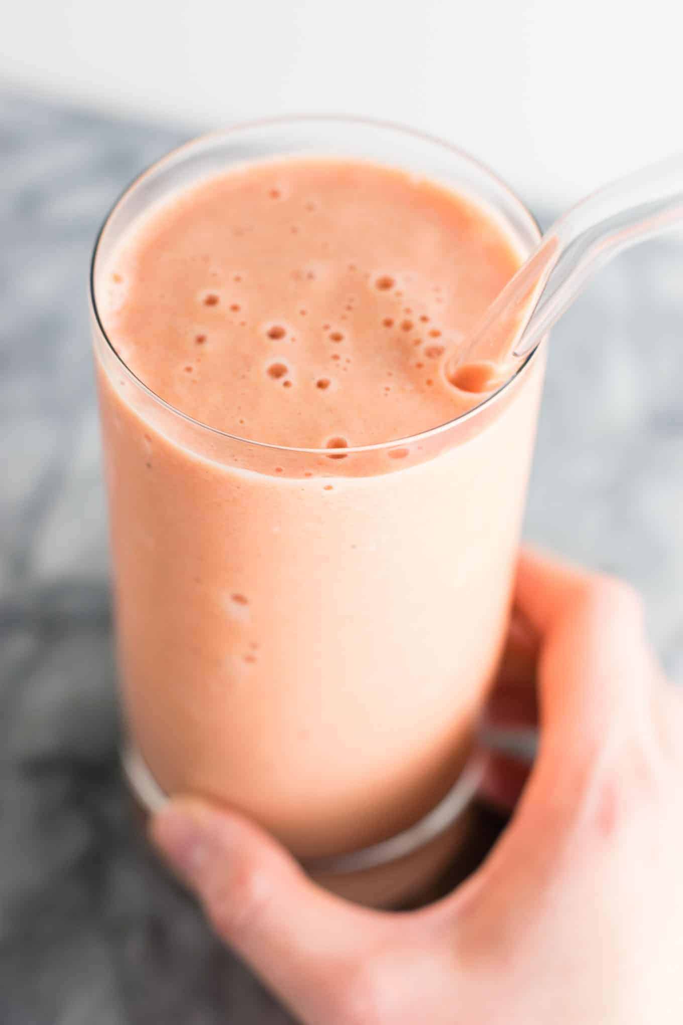 carrot cake smoothie in a glass with a glass straw