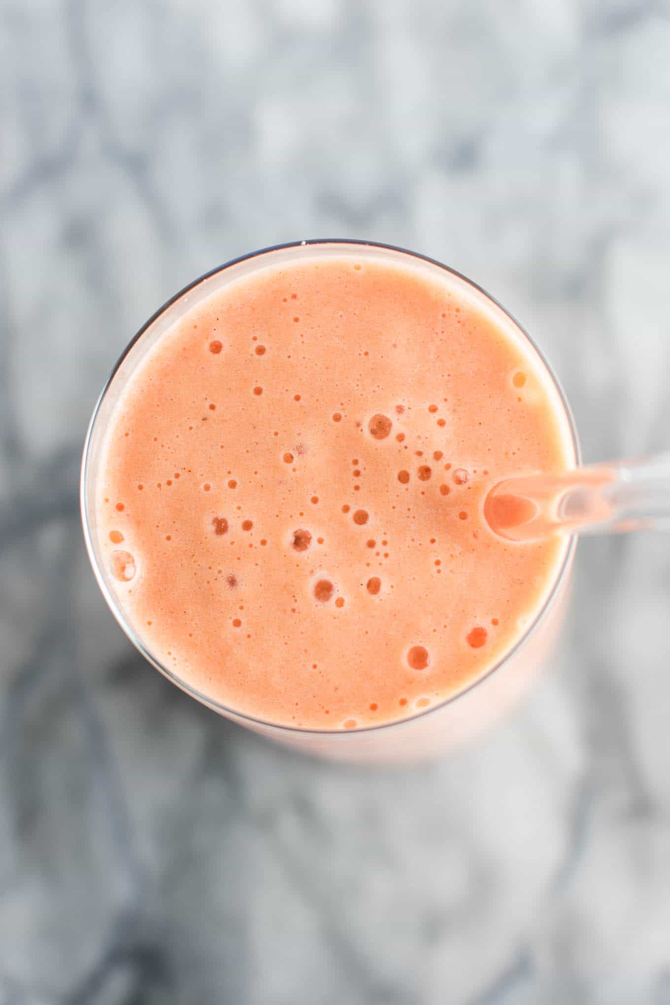 carrot cake smoothie in a glass with a glass straw