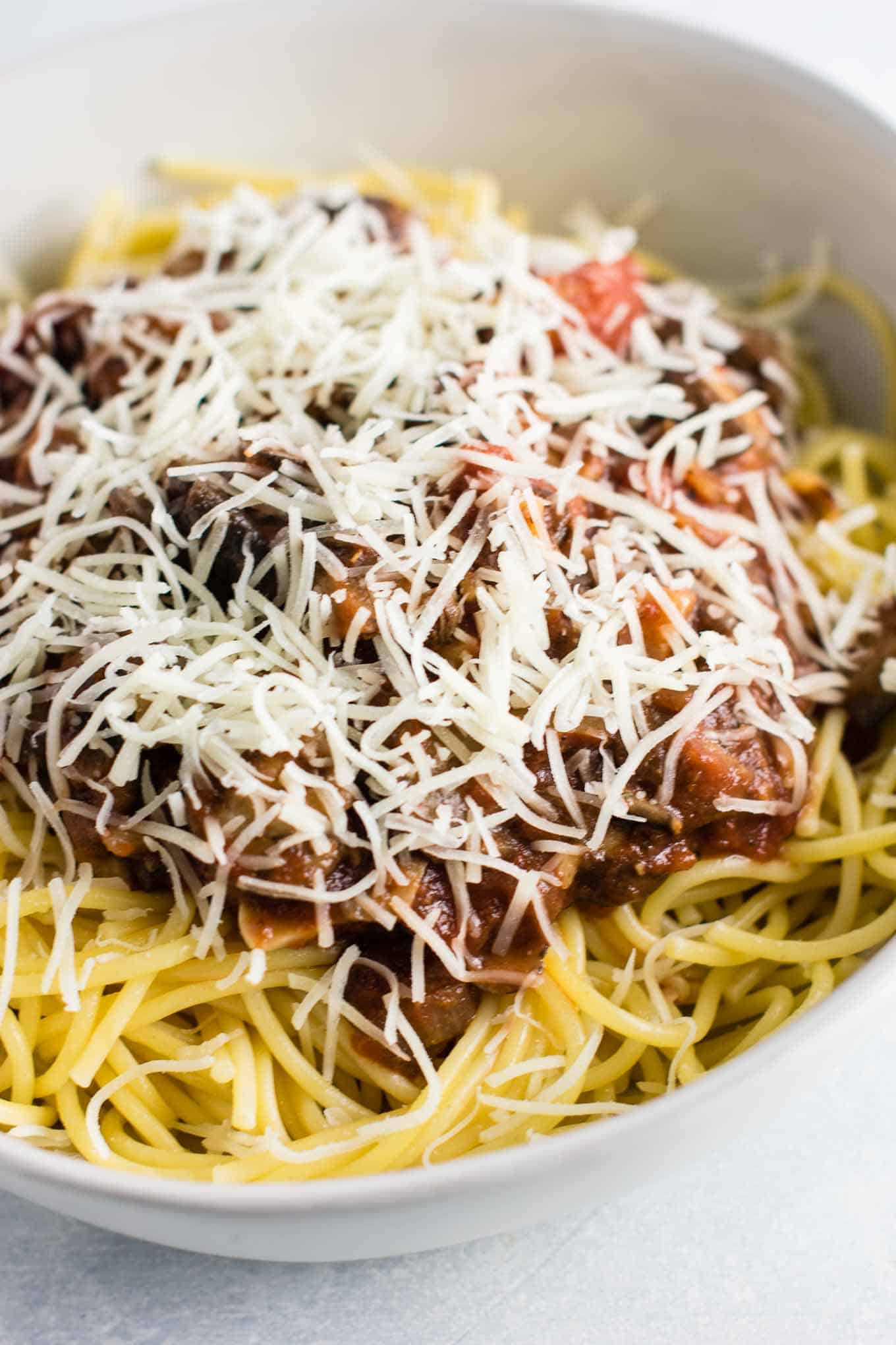 spaghetti in a bowl sprinkled with shredded mozzarella cheese