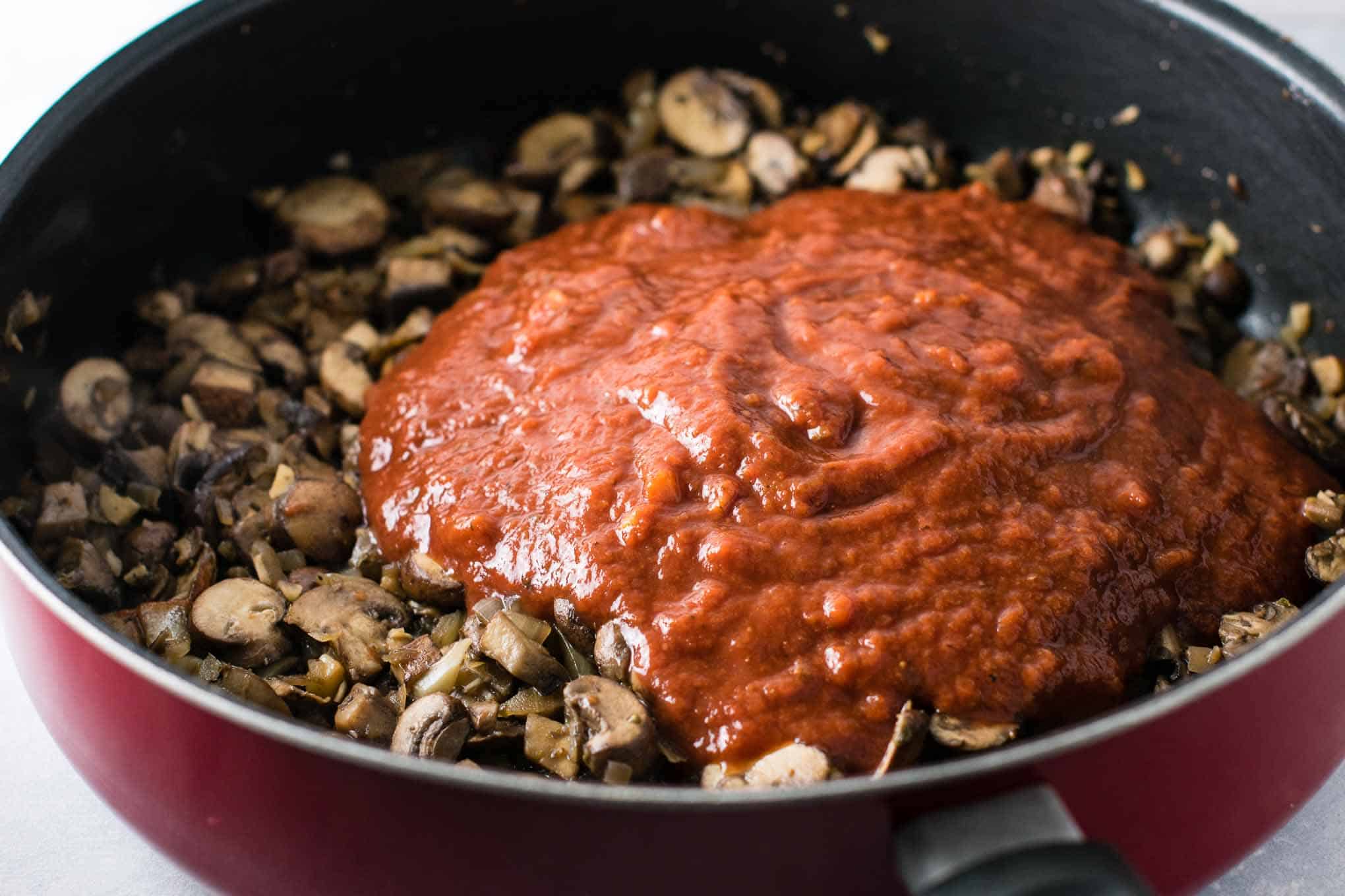 pasta sauce on top of the cooked mushrooms