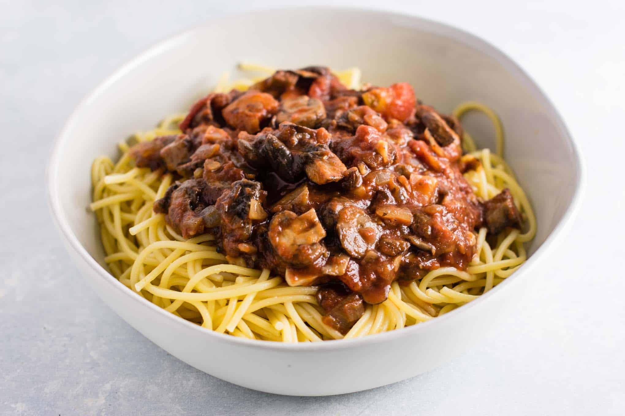 hearty vegetarian spaghetti sauce over white spaghetti noodles in a bowl