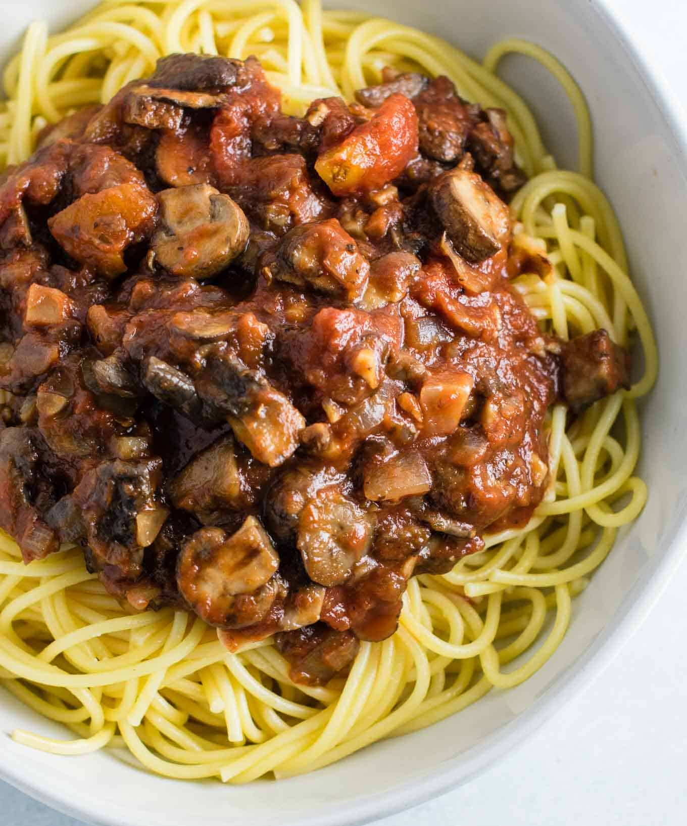 vegetarian mushroom spaghetti sauce over white spaghetti noodles in a white bowl