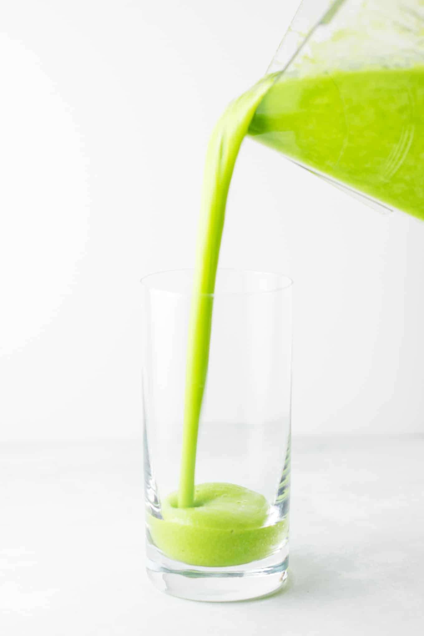 pouring the green smoothie into a glass