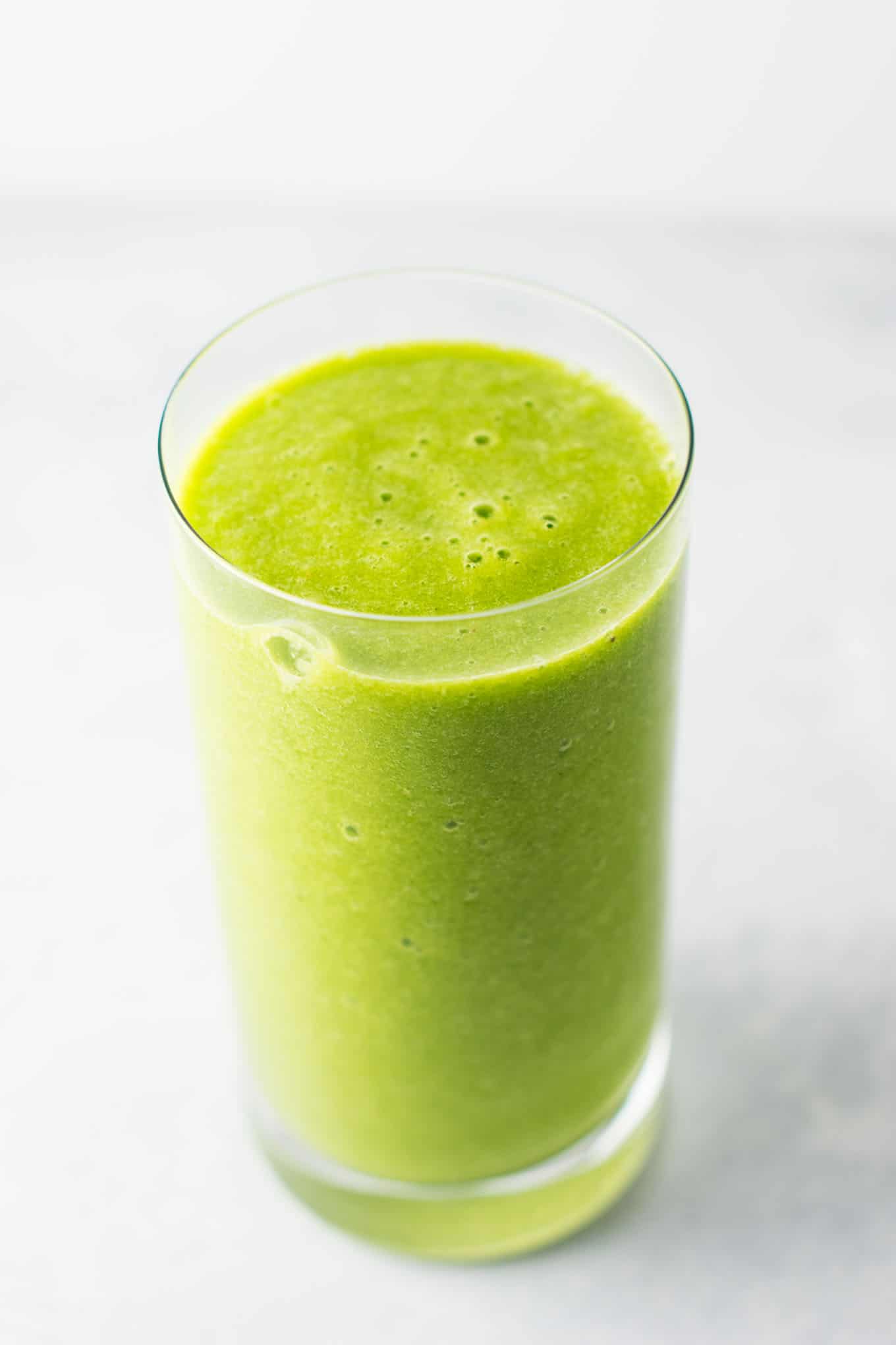 The BEST EVER green smoothie recipe made with kale, ginger, oranges, lemon, frozen banana, frozen peaches, and water. A ridiculously good for you delicious green smoothie that the whole family will love! #greensmoothierecipe #vegan #kale #drinks