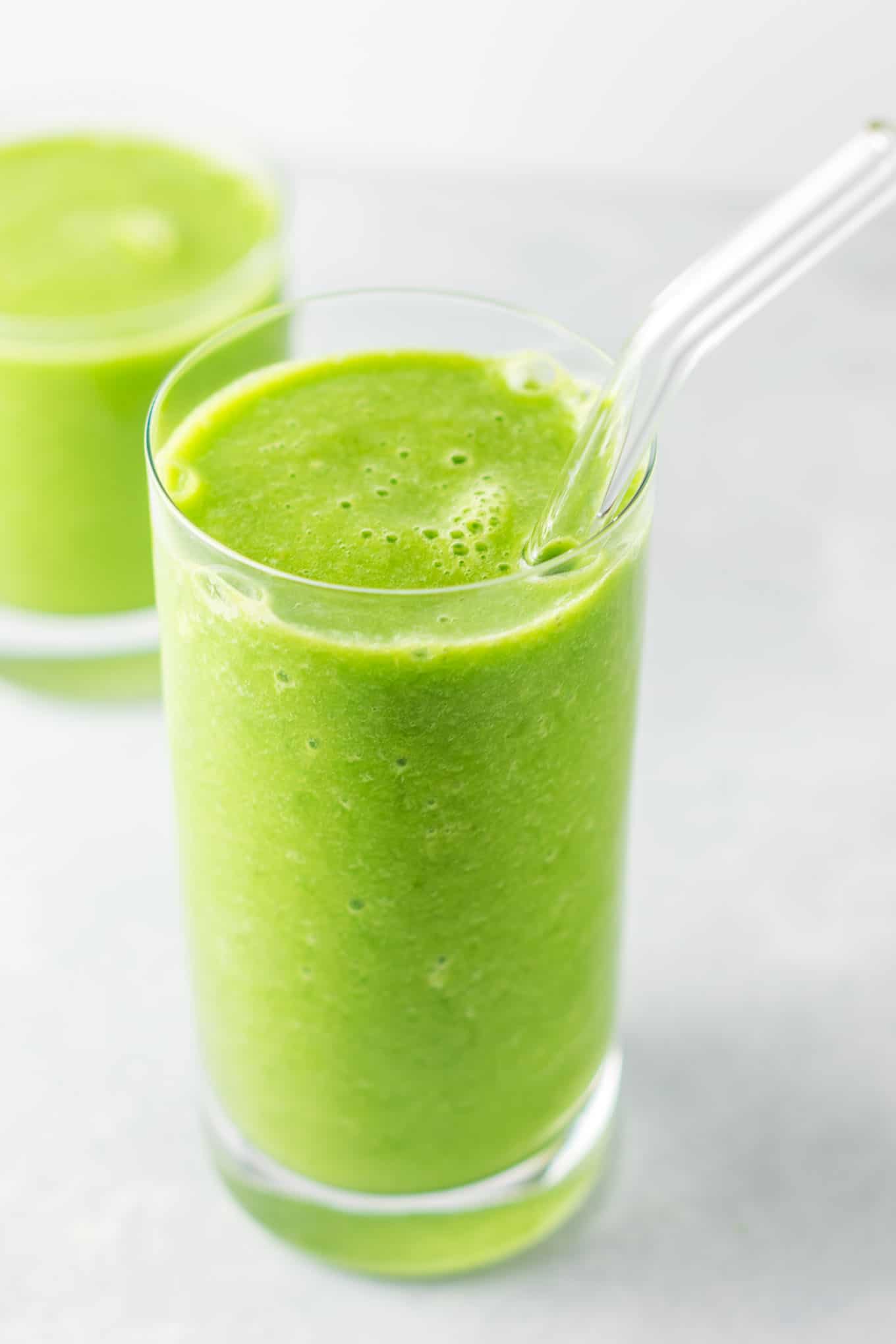 green smoothie in a glass with a straw